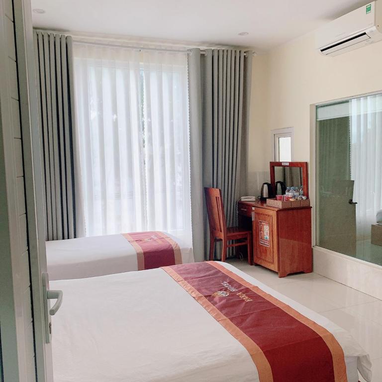 潘郎Khách Sạn FARA的酒店客房设有两张床、一张书桌和一个窗户。