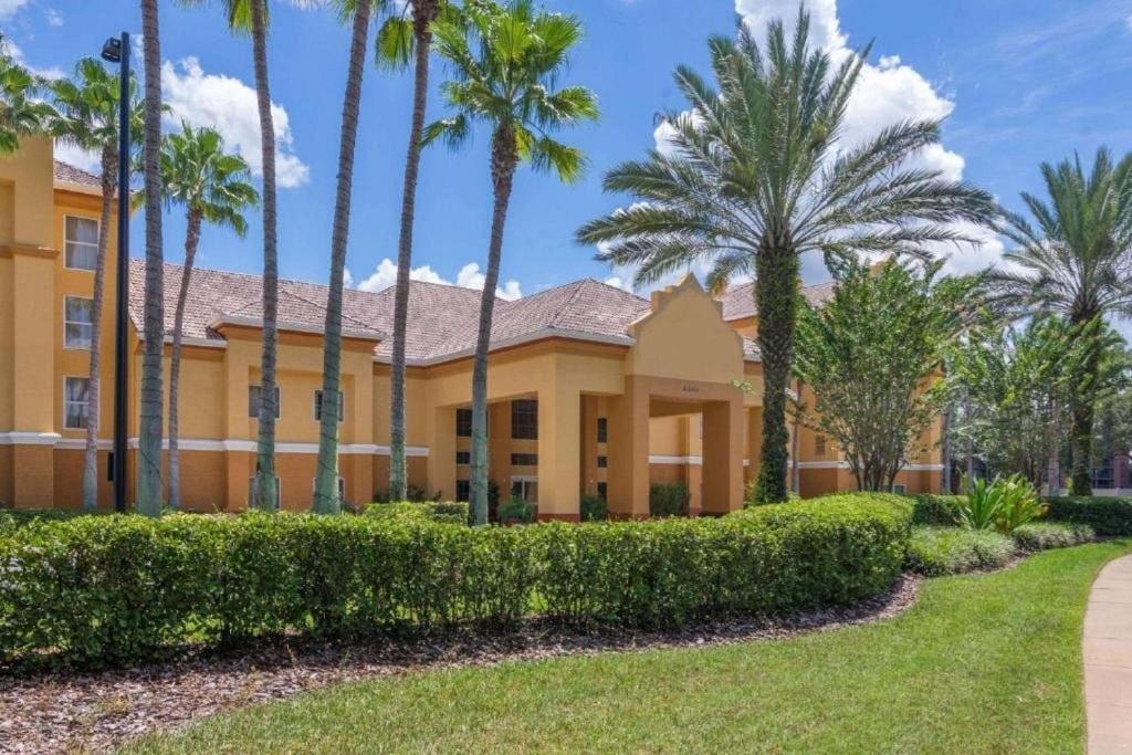 奥兰多SureStay Plus by Best Western Orlando Lake Buena Vista的一座棕榈树的黄色建筑