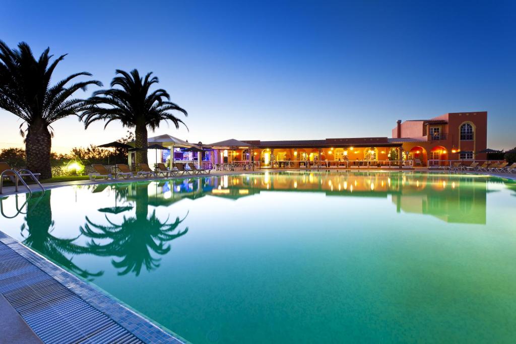 卡武埃鲁科利纳乡村酒店的一座棕榈树大型游泳池和一座建筑