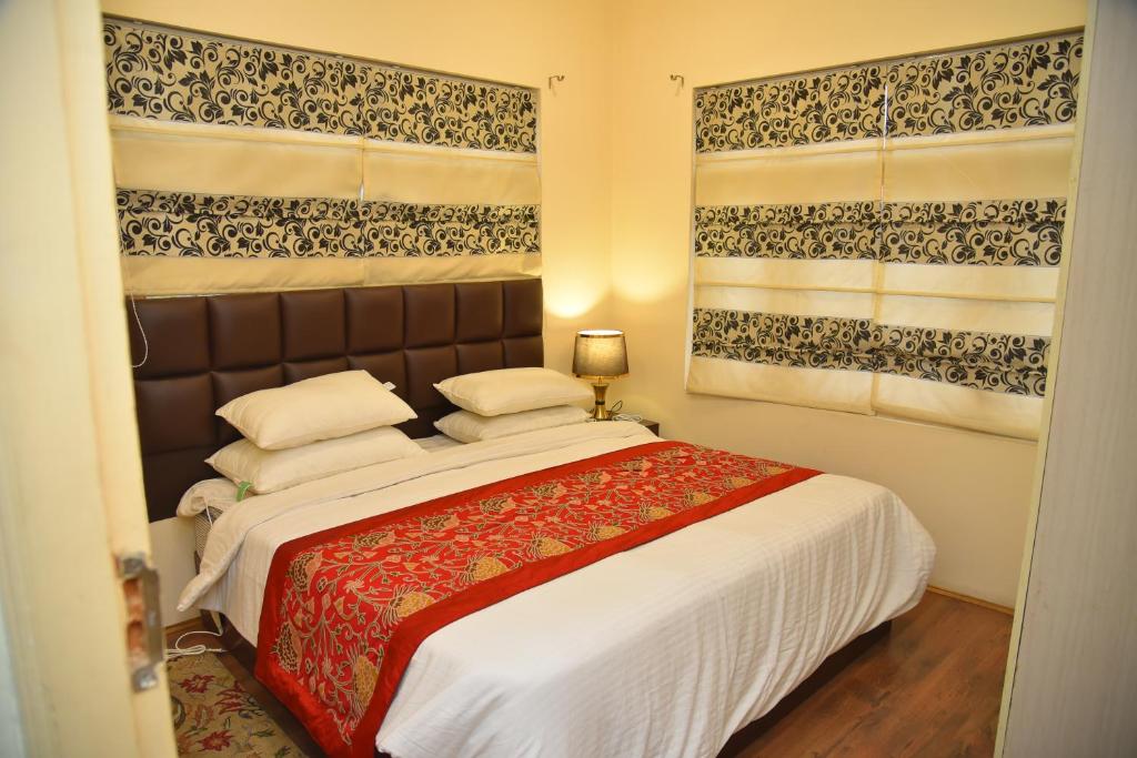 斯利那加Himalayan Sun Cottage的一间卧室设有一张大床和两个窗户。