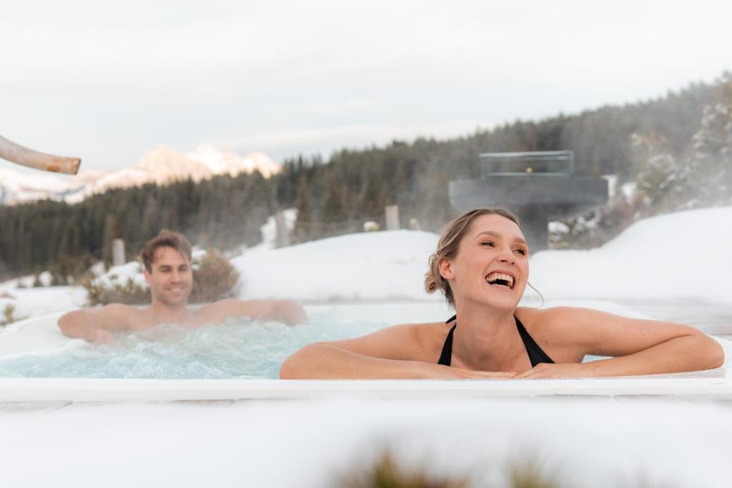 阿尔卑斯休斯山Dolomites Living Hotel Tirler的热水浴池中的男女