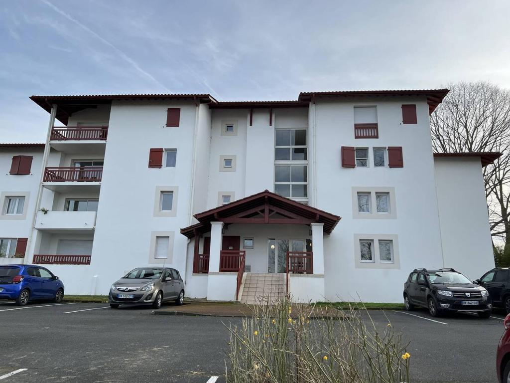 康博莱班Appartement Cambo-les-Bains, 2 pièces, 2 personnes - FR-1-495-74的一座白色的大建筑,汽车停在停车场