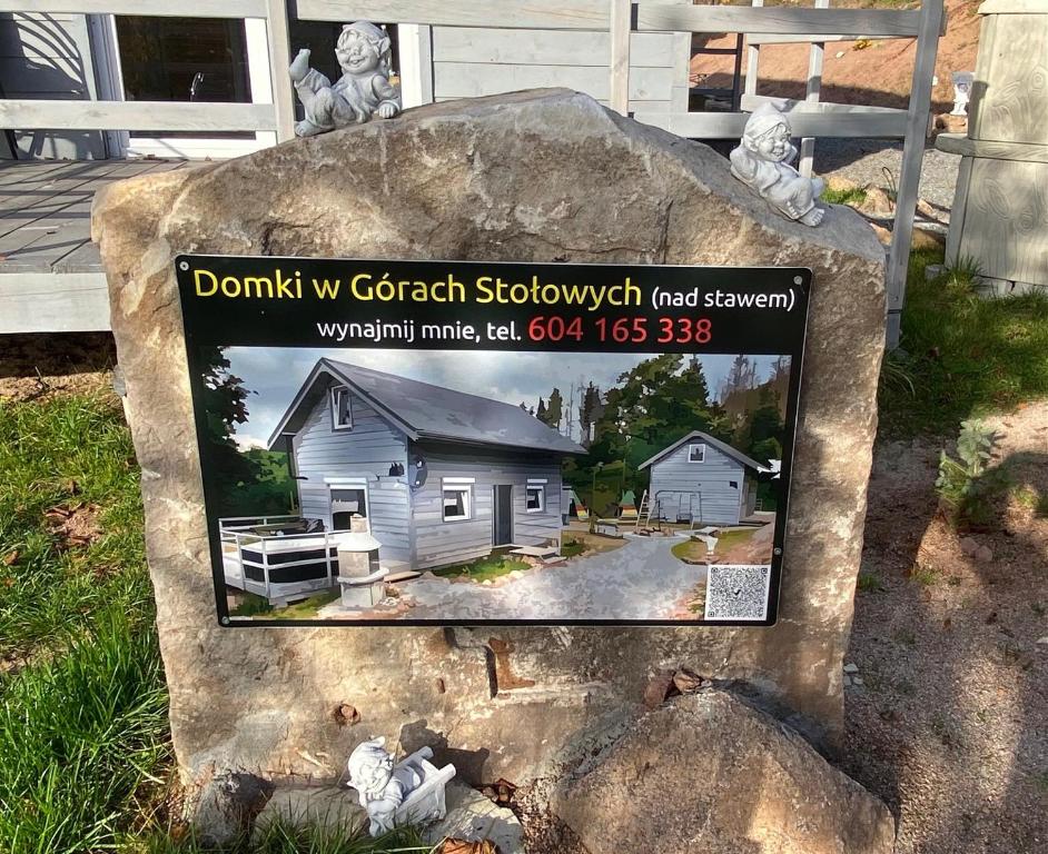 库多瓦-兹德鲁伊Domki w Górach Stołowych的一块石头上的标志,上面有房子的照片