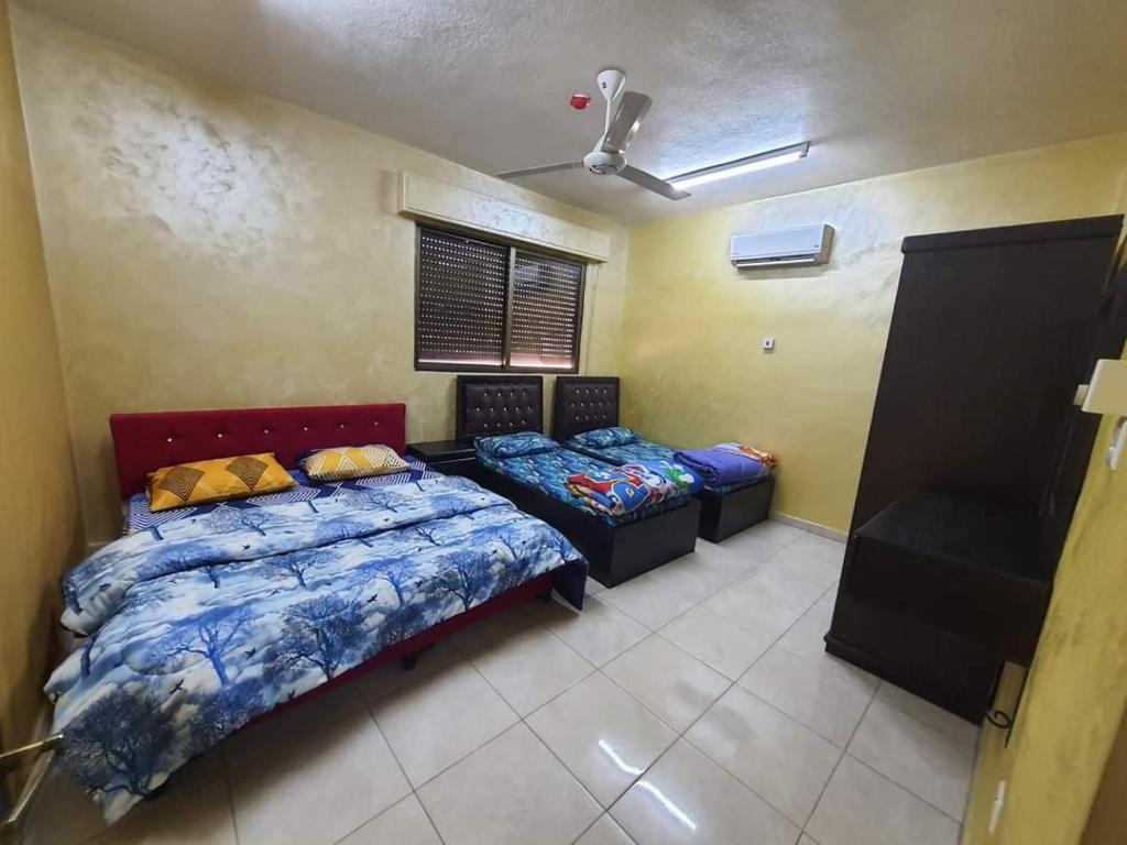 亚喀巴العاصم للشقق الفندقية ALASEM HOTEL APARTMENTS的一间卧室配有两张床和吊扇