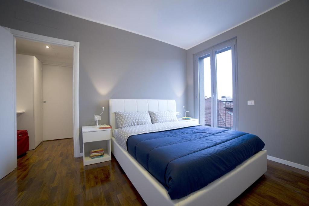 米兰皮阿内尔10号公寓式酒店的一间卧室设有蓝色的床和窗户。