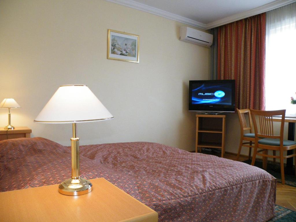 布达佩斯布达佩斯布达公寓式酒店的酒店客房,配有带灯具的床和电视
