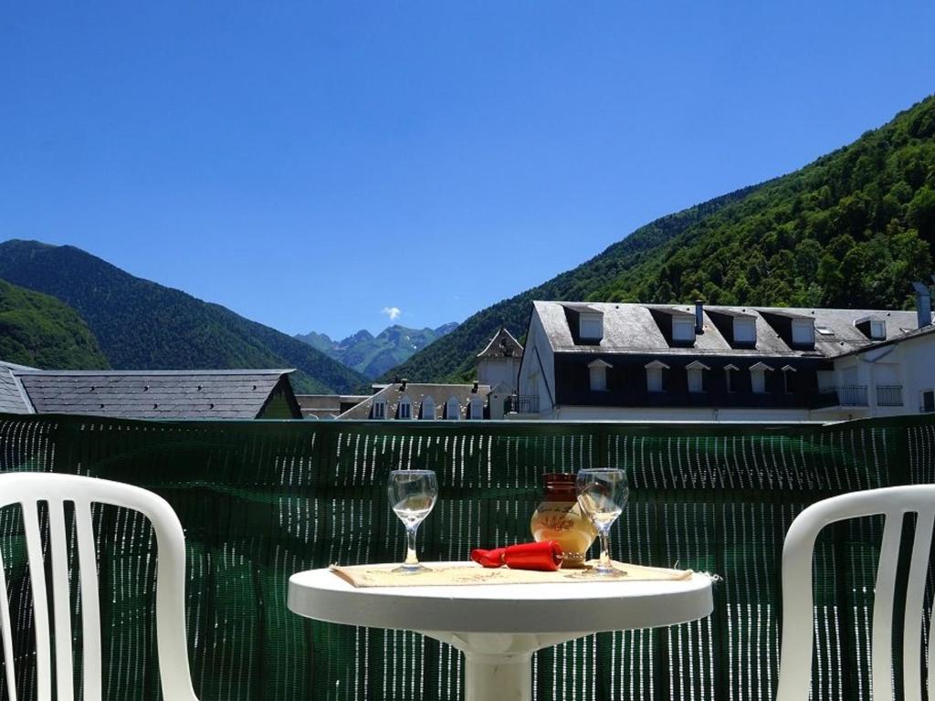 巴涅尔-德吕雄Appartement Bagnères-de-Luchon, 2 pièces, 4 personnes - FR-1-313-151的阳台上的桌子和两杯酒杯