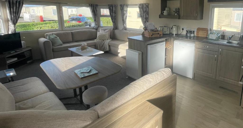 纽顿Trecco Bay Porthcawl Caravan 8 berth PALMS 4的厨房以及带沙发和桌子的客厅。