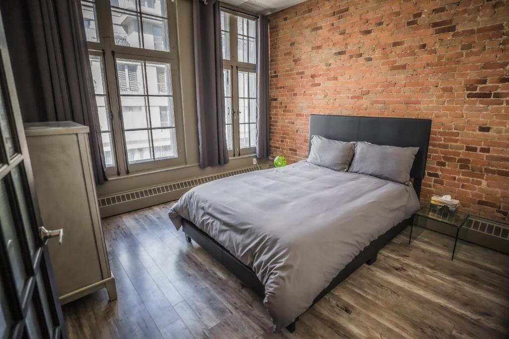 蒙特利尔Le 402的一间卧室设有一张带砖墙的大床