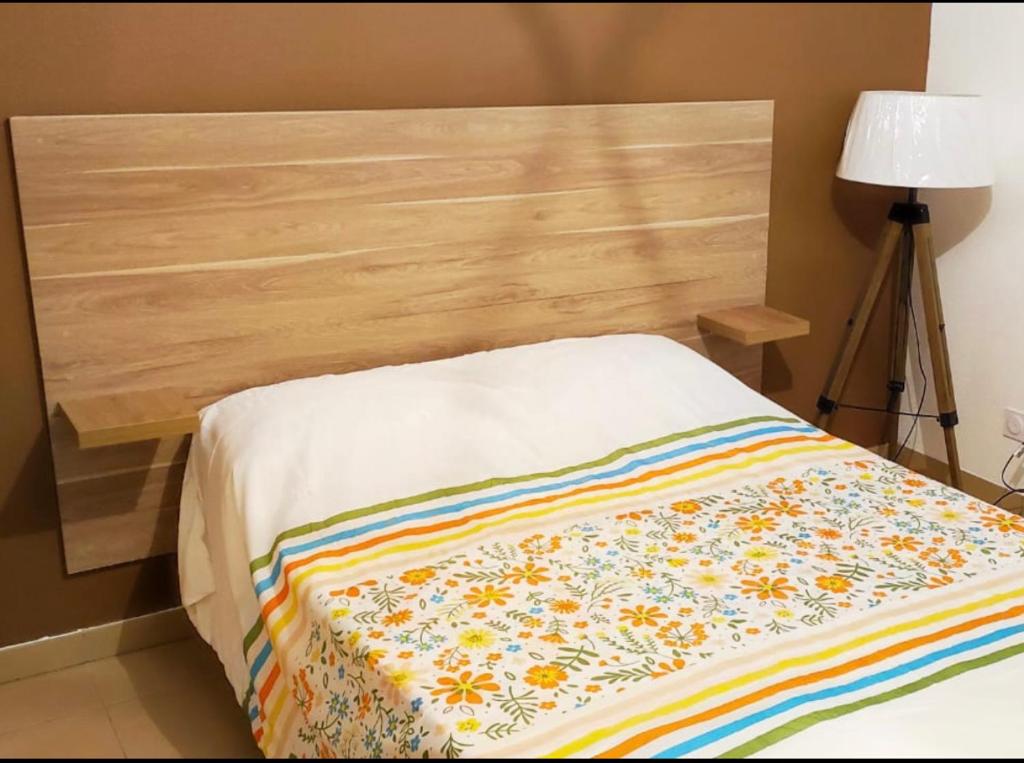 马赛Les docks libres sud的一张带木制床头板的床,上面有色彩缤纷的毯子