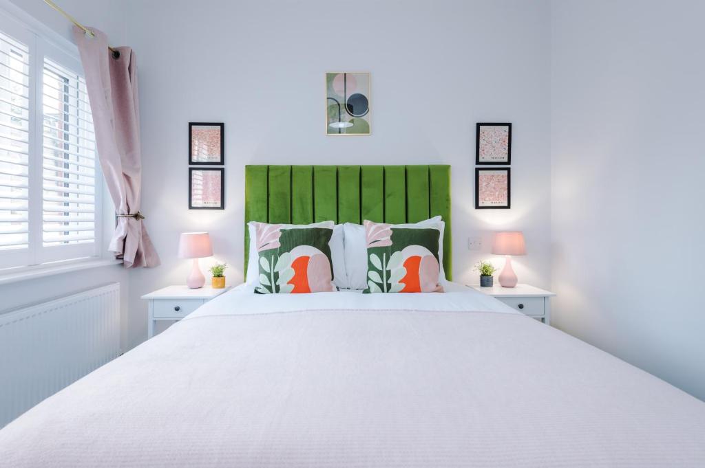 考文垂Beechwood Lodge Serviced Apartment的一间卧室配有一张白色大床和绿色床头板