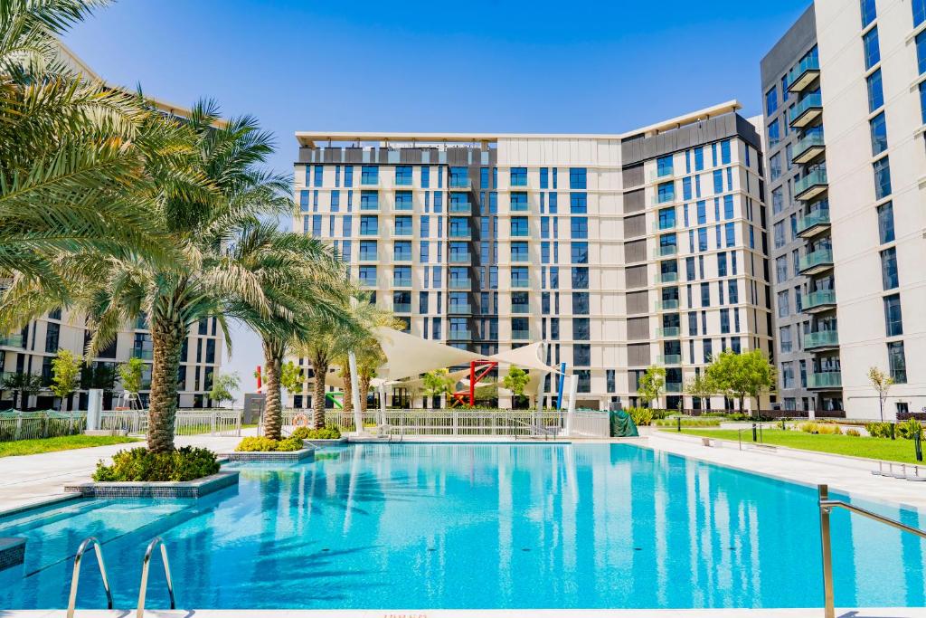 迪拜Expo Village Serviced Apartments的一座楼前棕榈树游泳池