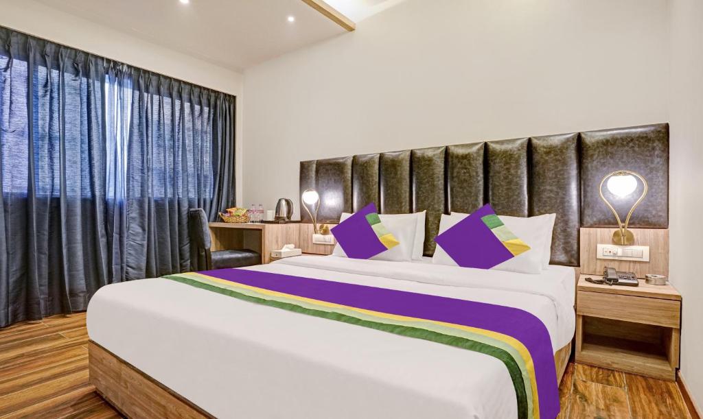 孟买Treebo Tryst Widlor Boutique的一间卧室配有一张大床,提供紫色和绿色枕头