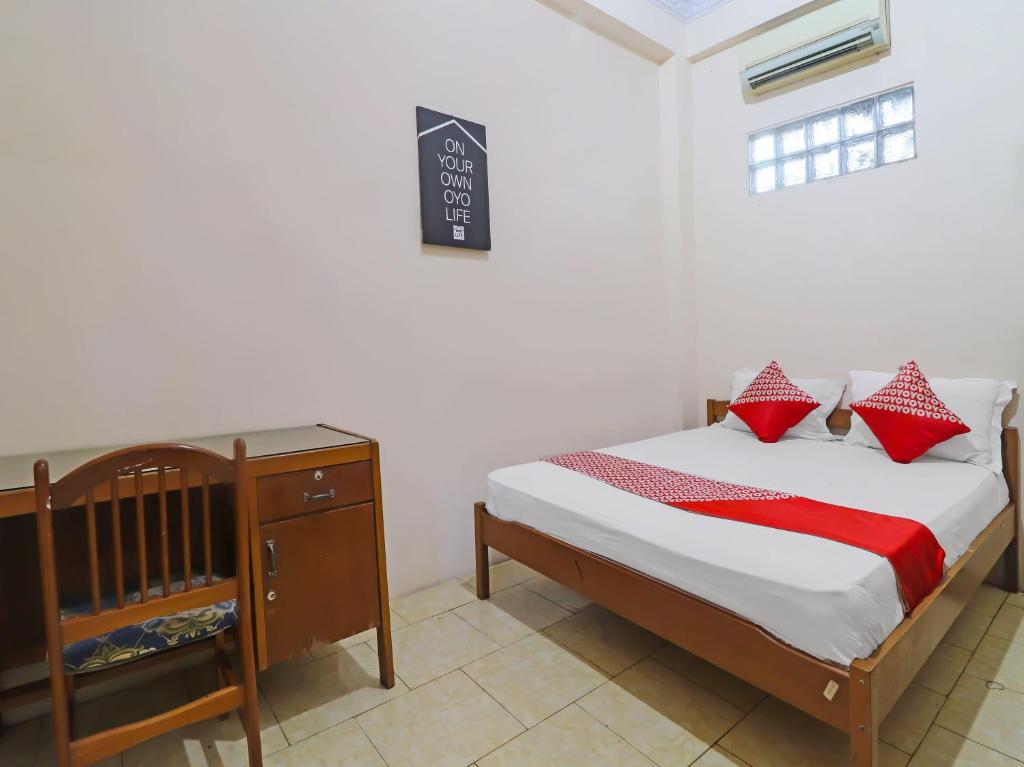 占碑市OYO 2899 Ardilia Bandara Syariah的一间卧室配有一张带红色枕头的床和一张婴儿床。