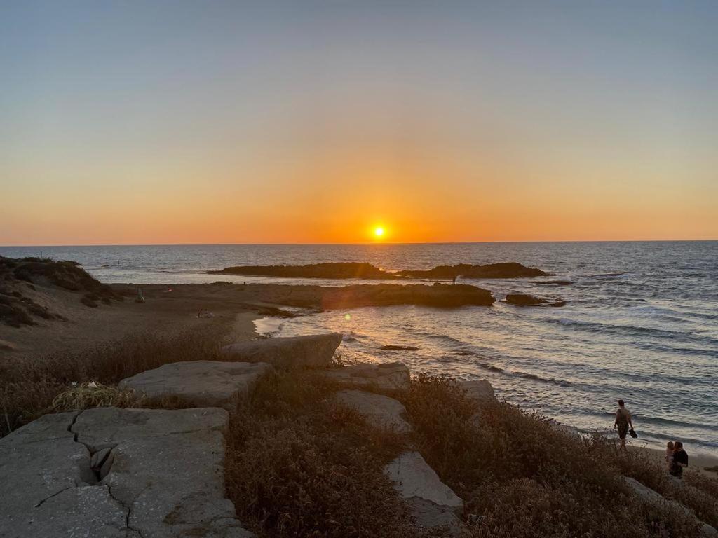 亚实基伦Sunset and sea view, wifi and more的海滩上的人漫步的海上日落