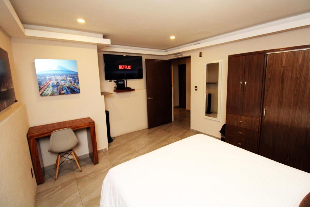 墨西哥城OSLO 5的一间卧室配有一张床、一台电视和一把椅子