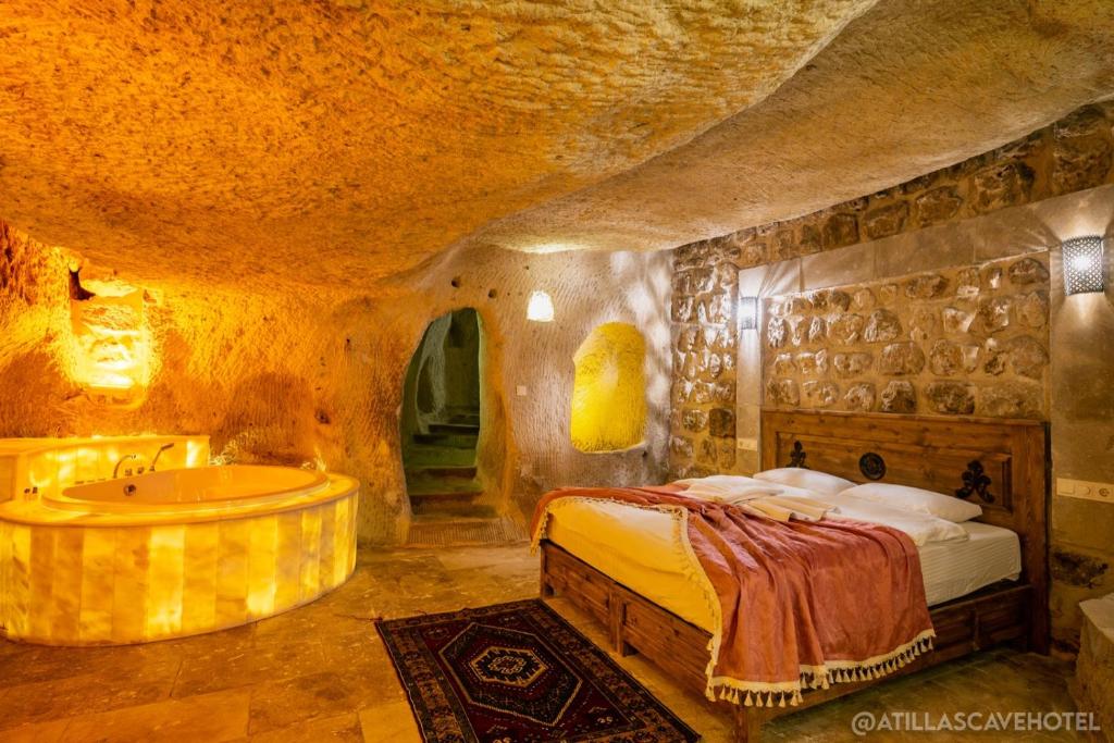 内夫谢希尔Atilla's Cave Hotel的一间洞穴内的卧室,配有一张床和一个浴缸