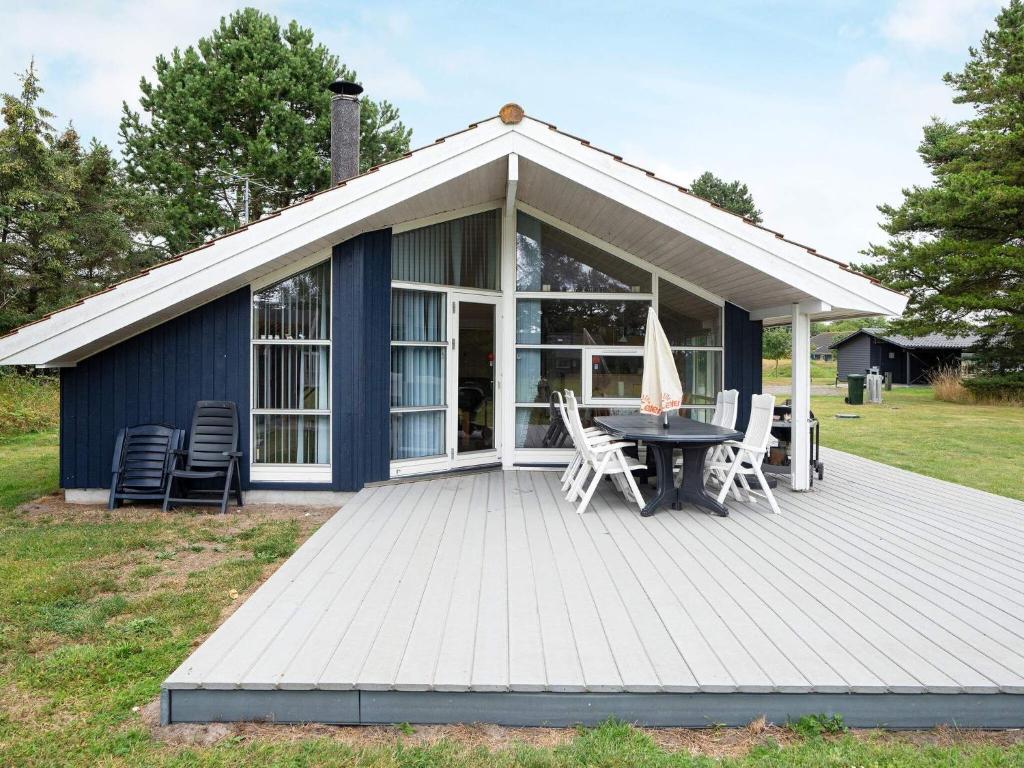 克兰尼茨Three-Bedroom Holiday home in Rødby 6的蓝色小屋 - 带桌椅的甲板