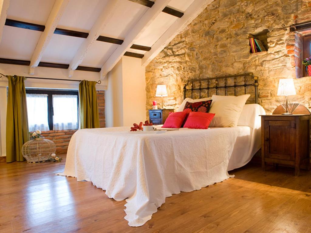 苏安塞斯波萨达圣安娜酒店的一间卧室设有一张带石墙的大床