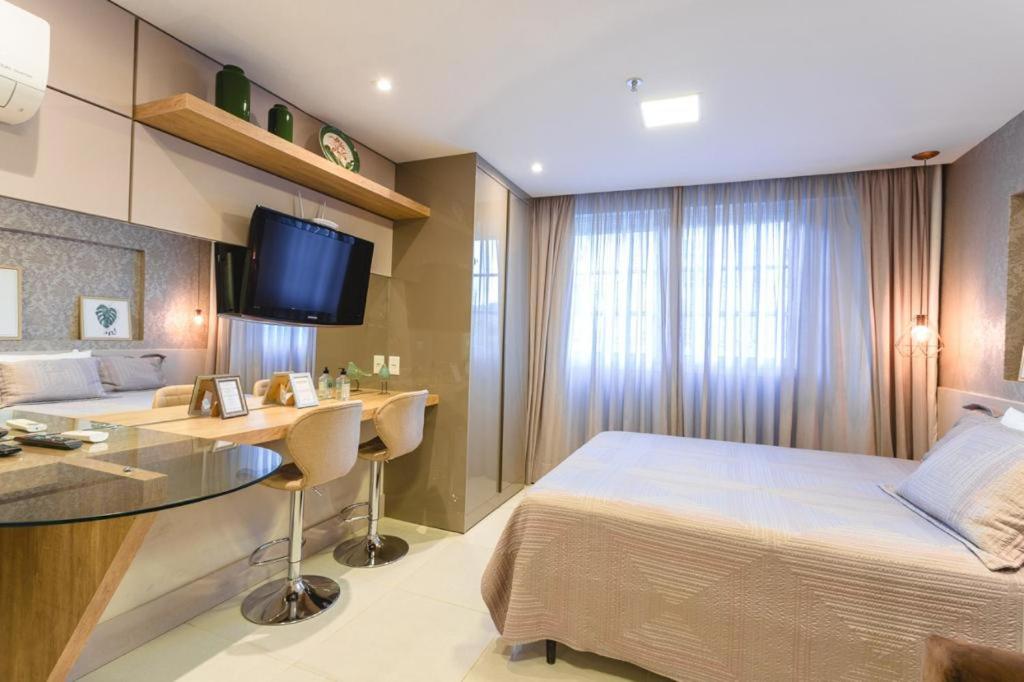 伊泰帕瓦Apart Mangabeiras Granja Brasil Itaipava的一间卧室配有一张床、一张书桌和一台电视。