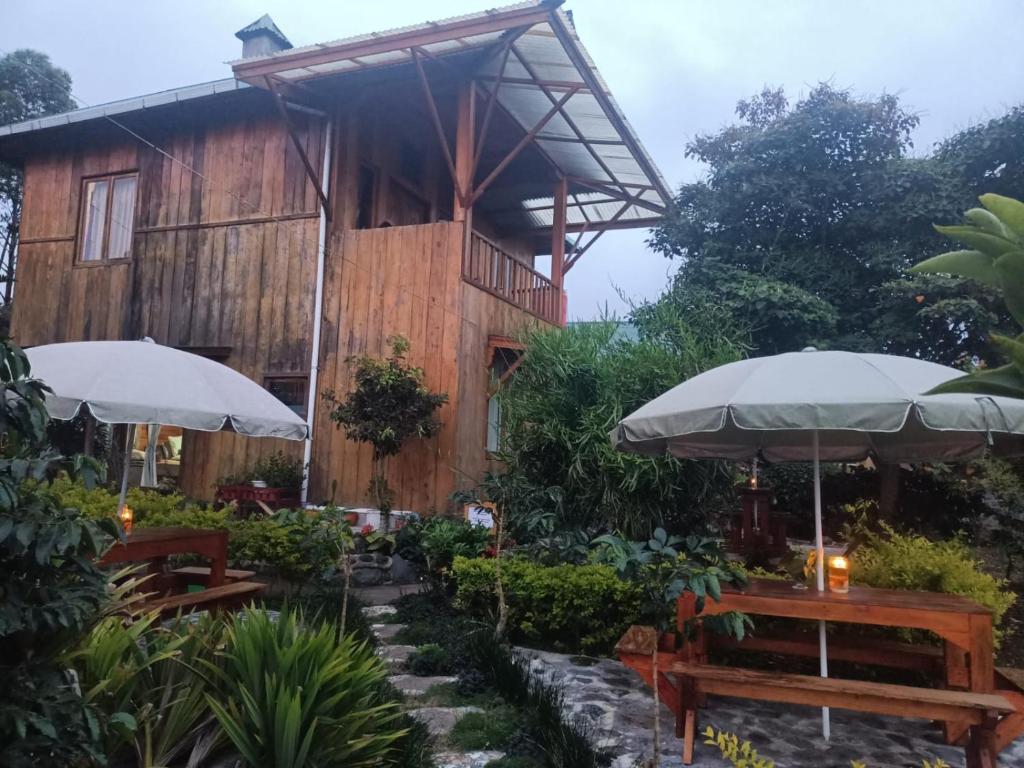 Kayu AroPelangi Guest House的前面有桌子和伞的建筑