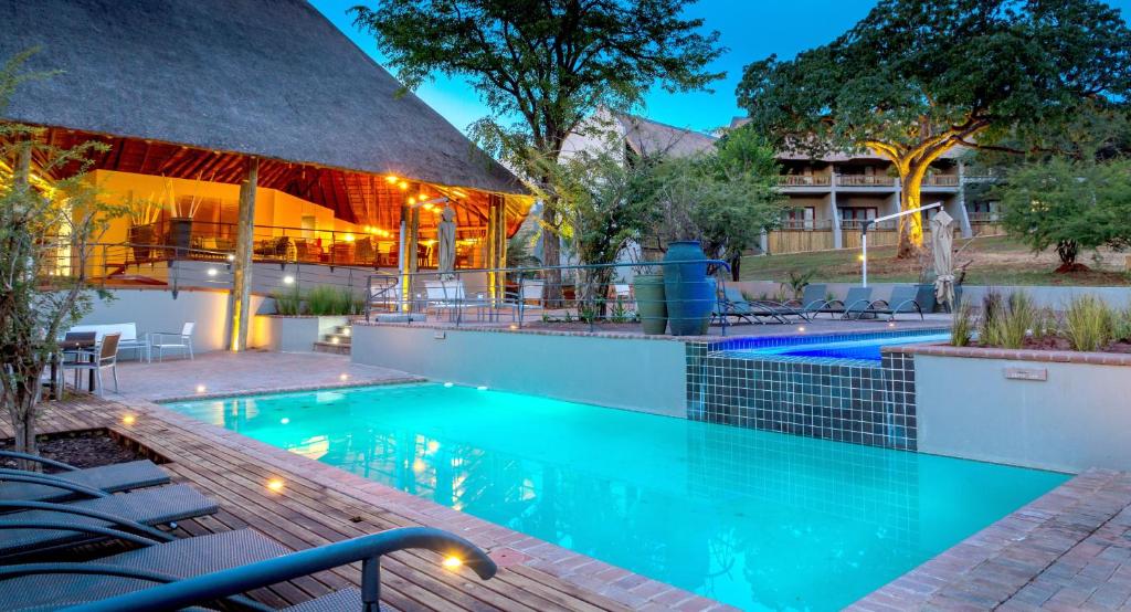 卡萨内Chobe Safari Lodges的一座带椅子的游泳池以及一座建筑