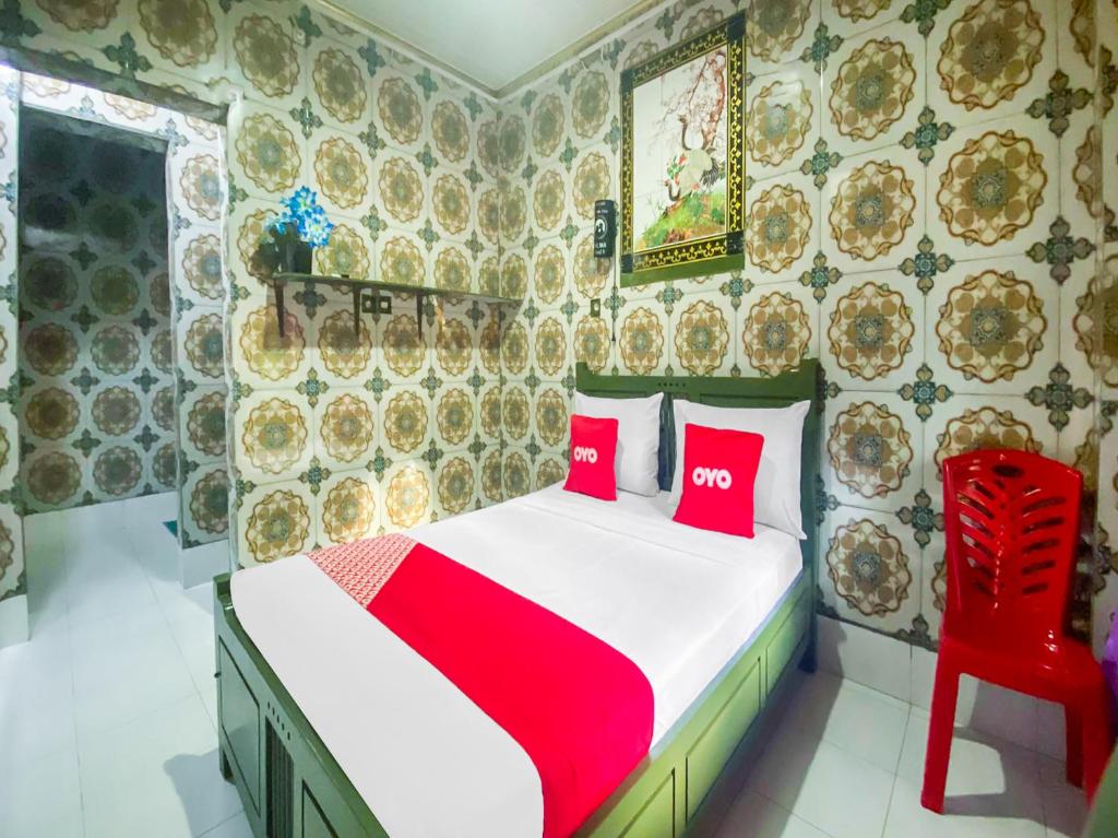 古邦OYO 2518 Wilma Hotel Ii Premier的一间卧室配有一张带两个红色枕头的床