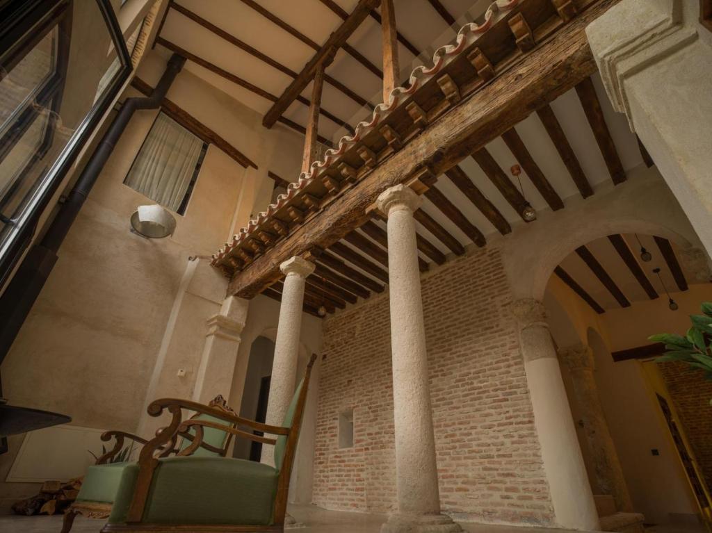 阿尔卡拉德荷那利斯Casa de los Mendoza - Casa Solariega en el casco histórico的建筑里带圆柱和椅子的房间