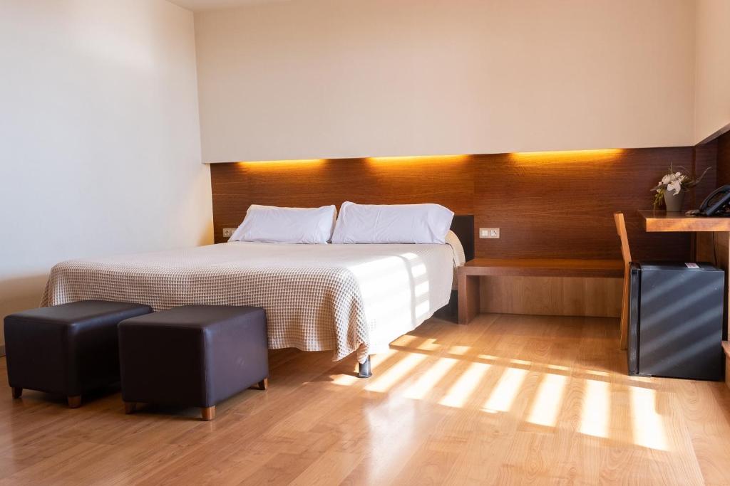 巴塞罗那Hotel Turin Barcelona的一间卧室配有一张床和两张凳子