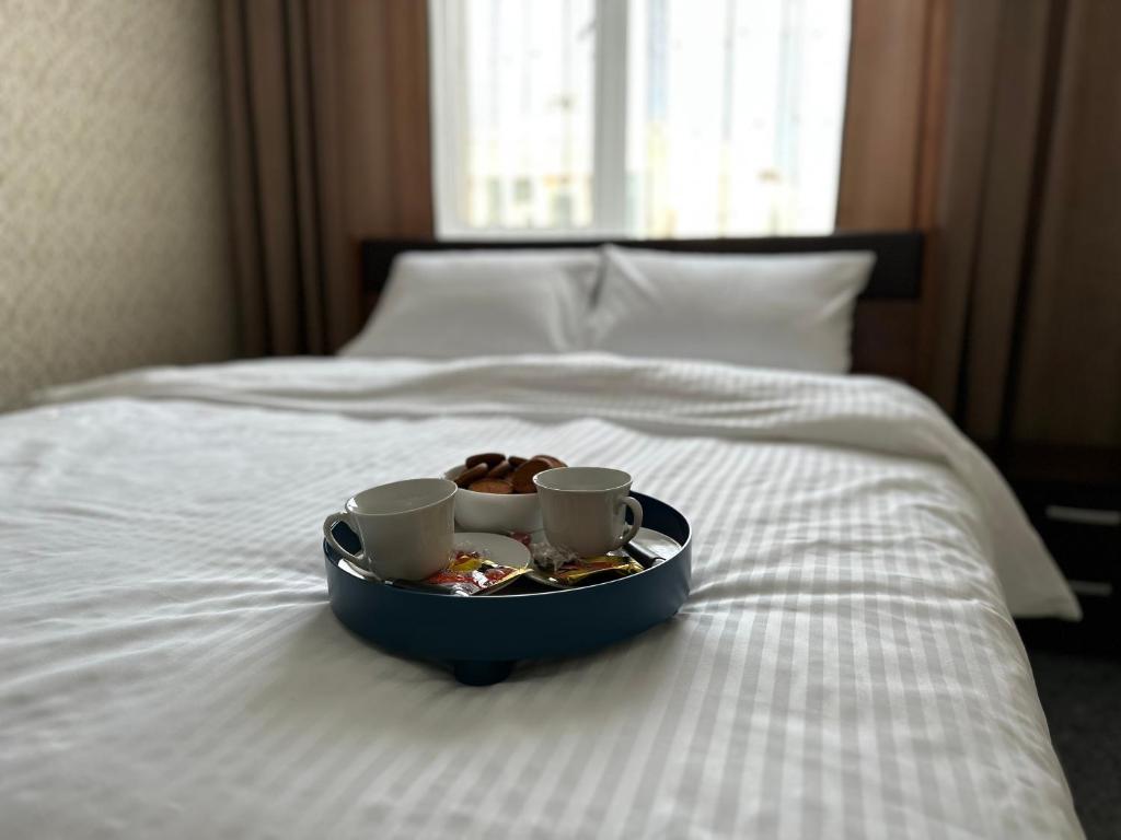 阿斯塔纳Апартаменты Миллениум 2的床上的托盘,上面有两杯和一只甜甜圈