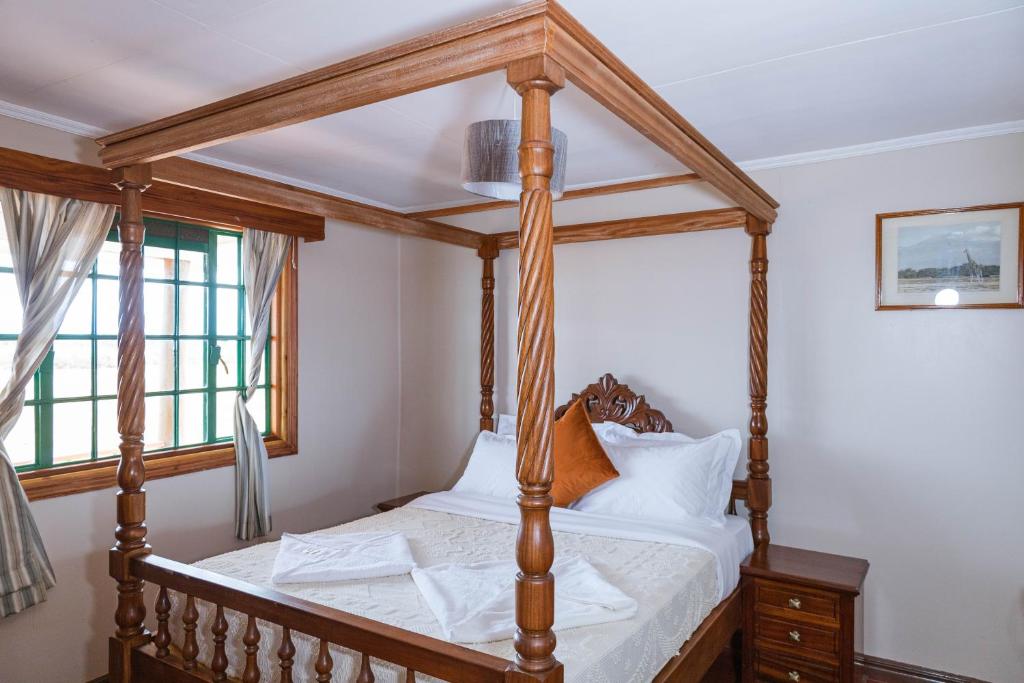 安博塞利Wild Amboseli Ndovu Cottage.的配有窗户的客房内的一张木制四柱床