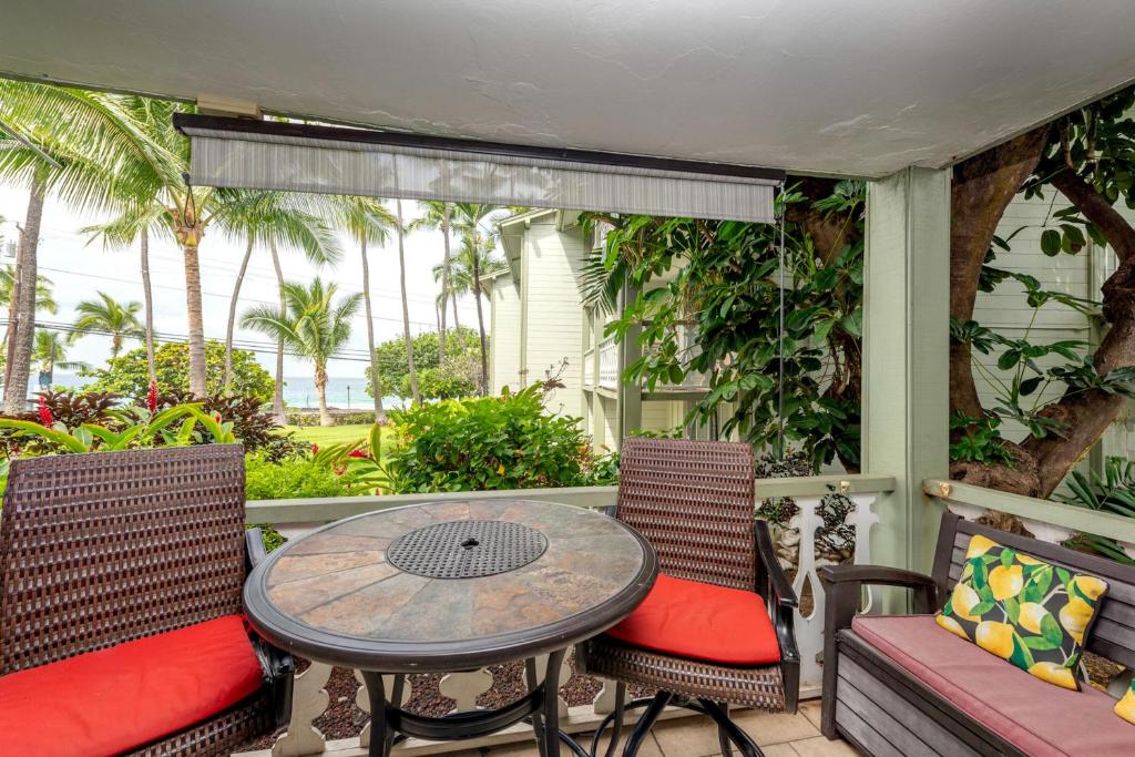 科纳Kona Islander Inn 147 Tropical Oasis的一个带桌椅和棕榈树的门廊