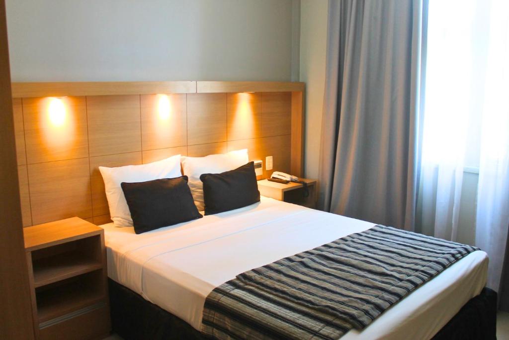 里约热内卢Hotel Atlântico Tower的一间卧室配有一张大床和木制床头板