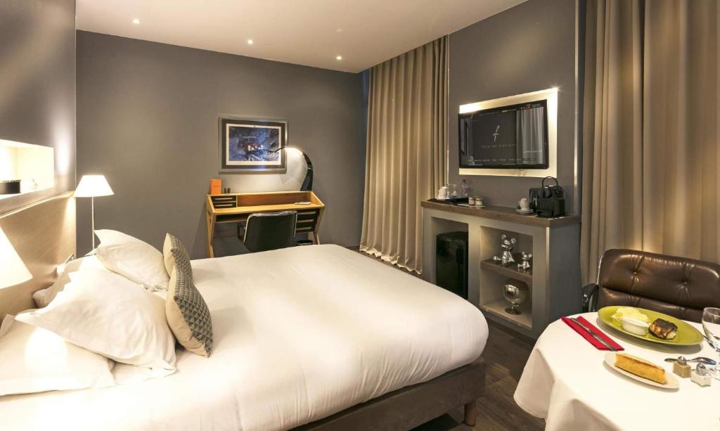 瓦朗斯法兰西酒店的酒店客房设有一张大床和一张书桌。
