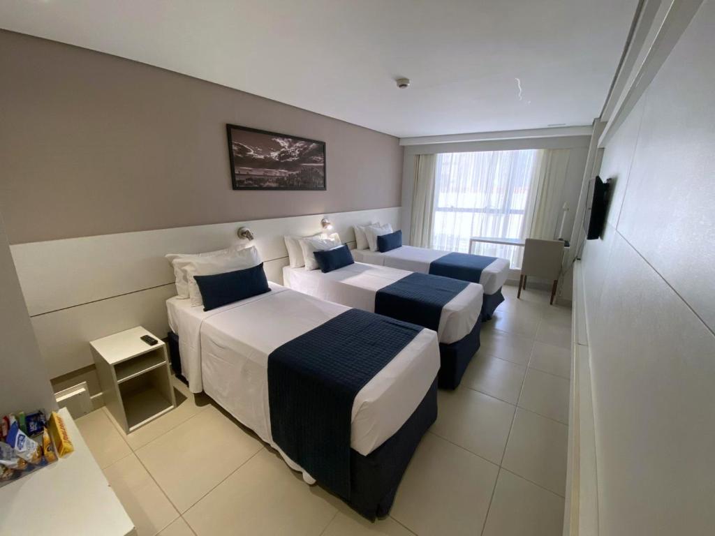若昂佩索阿Hotel Manaíra的酒店客房设有三张床和电视。