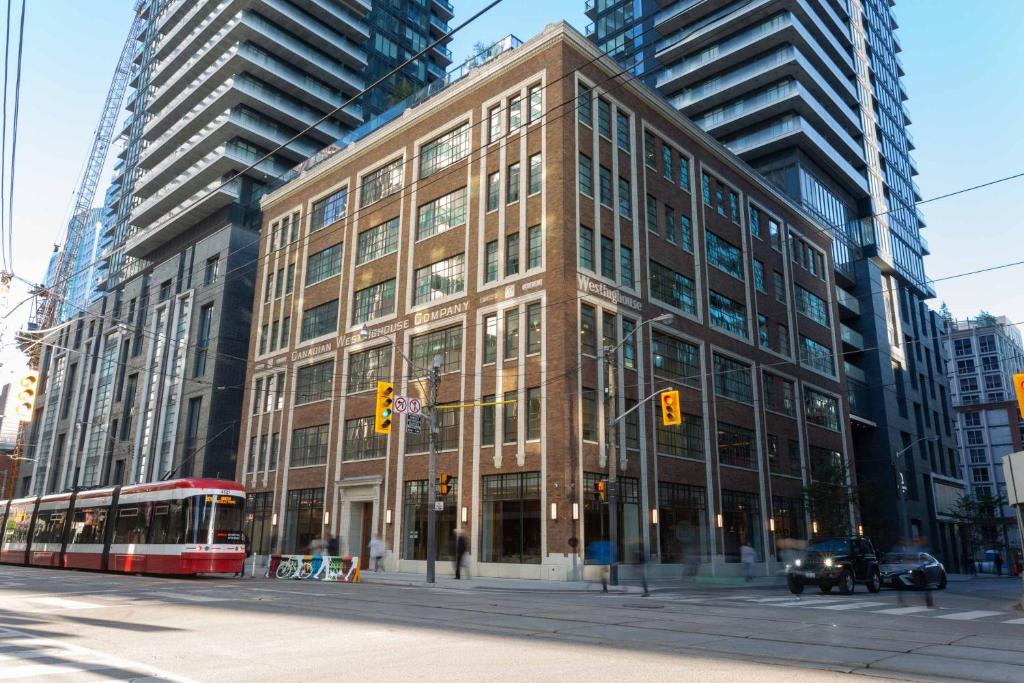 多伦多Sutton Place Hotel Toronto的一条城市街道上的大建筑,有一辆公共汽车