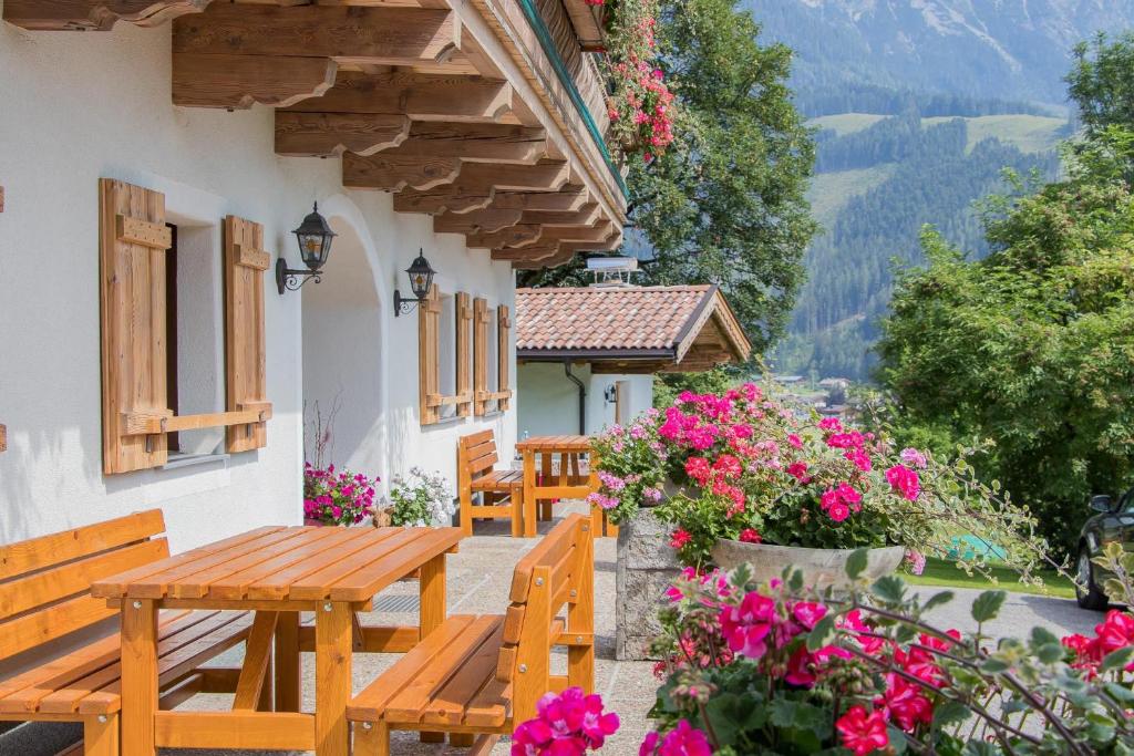 莱奥冈Pöchtlhof的阳台上设有一张木桌和长凳,阳台上摆放着鲜花