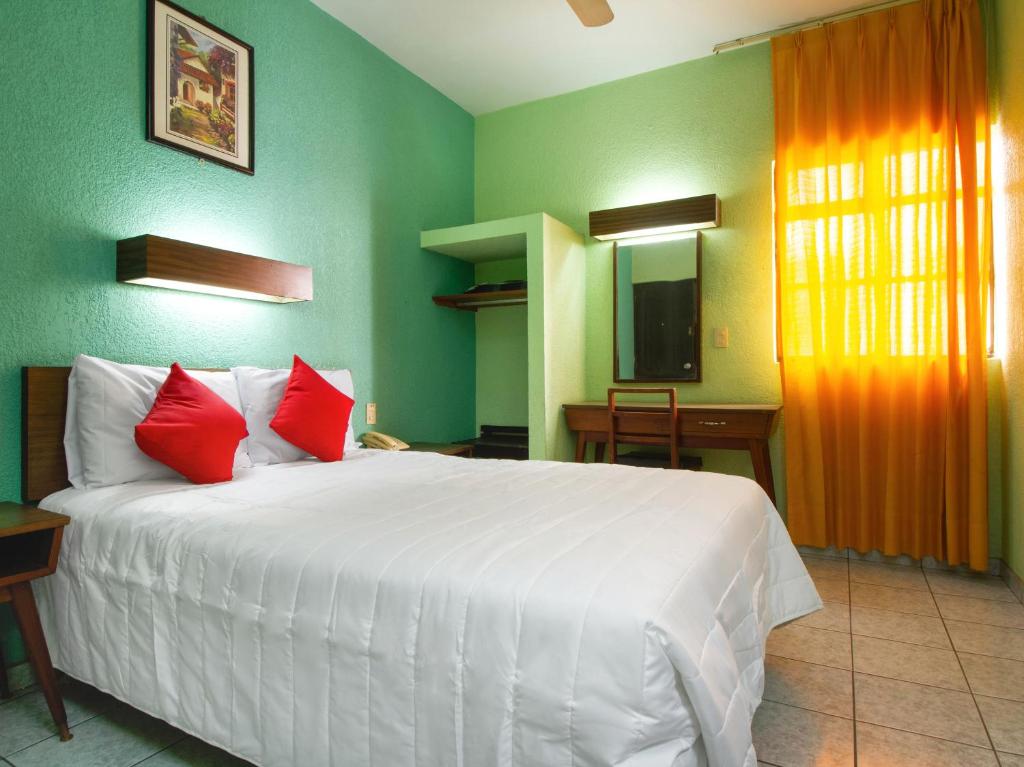 瓜达拉哈拉Hotel Canada的卧室配有带红色枕头的大型白色床