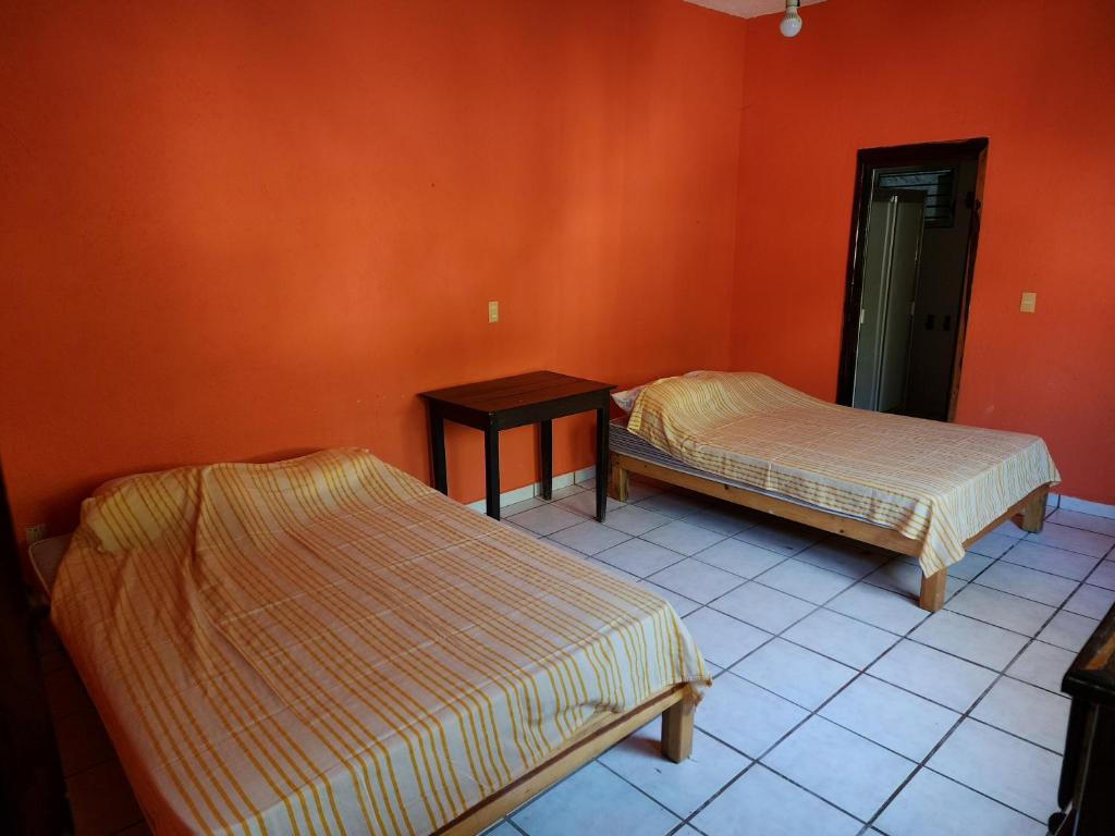 圣帕特里西奥梅拉克CASA PLAYITA MELAQUE的橙色墙壁客房的两张床