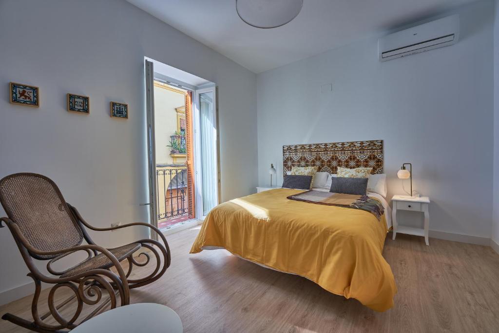 塞维利亚Casa Pureza的一间卧室配有一张带椅子的床和一扇窗户