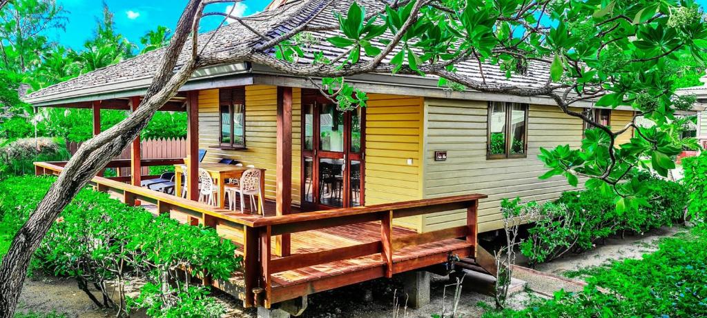 TemaeMOOREA - The Golden Reef Bungalow Nuku Hiva的黄色的房屋,设有大型木甲板