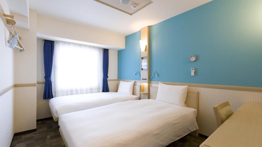 TorideToyoko Inn Toride-eki Higashi-guchi的酒店客房设有两张床和窗户。