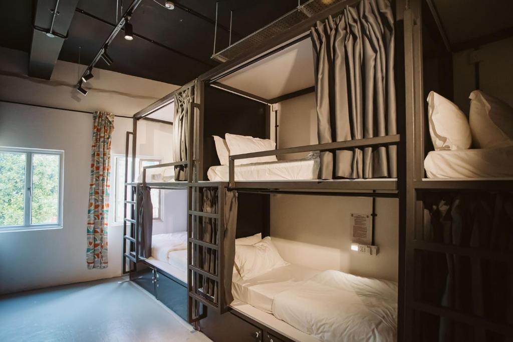 新加坡7 Wonders Hostel @ Boat Quay的客房设有三张双层床,配有白色床单