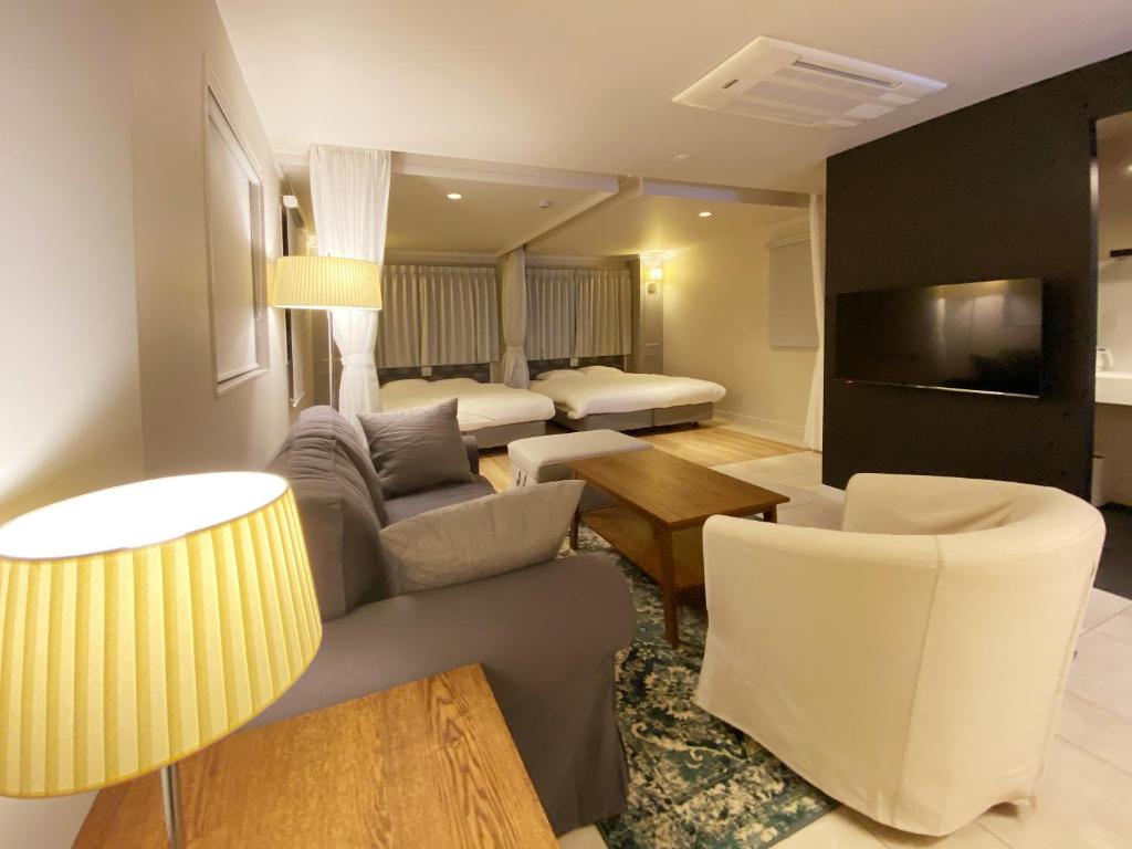 福冈precious days inn的客厅配有沙发、椅子和电视