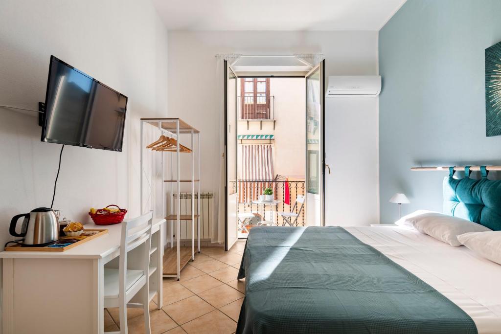 巴勒莫Punto al Capo Appartamento intero o stanze matrimoniali con bagno privato的一间卧室配有一张床、一张书桌和一台电视
