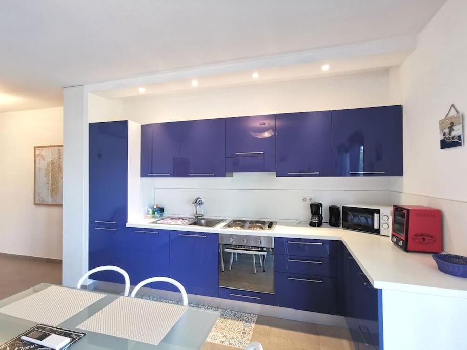 圣弗洛朗Joli appartement face à la mer- St Florent的厨房配有蓝色橱柜和红色用具的桌子