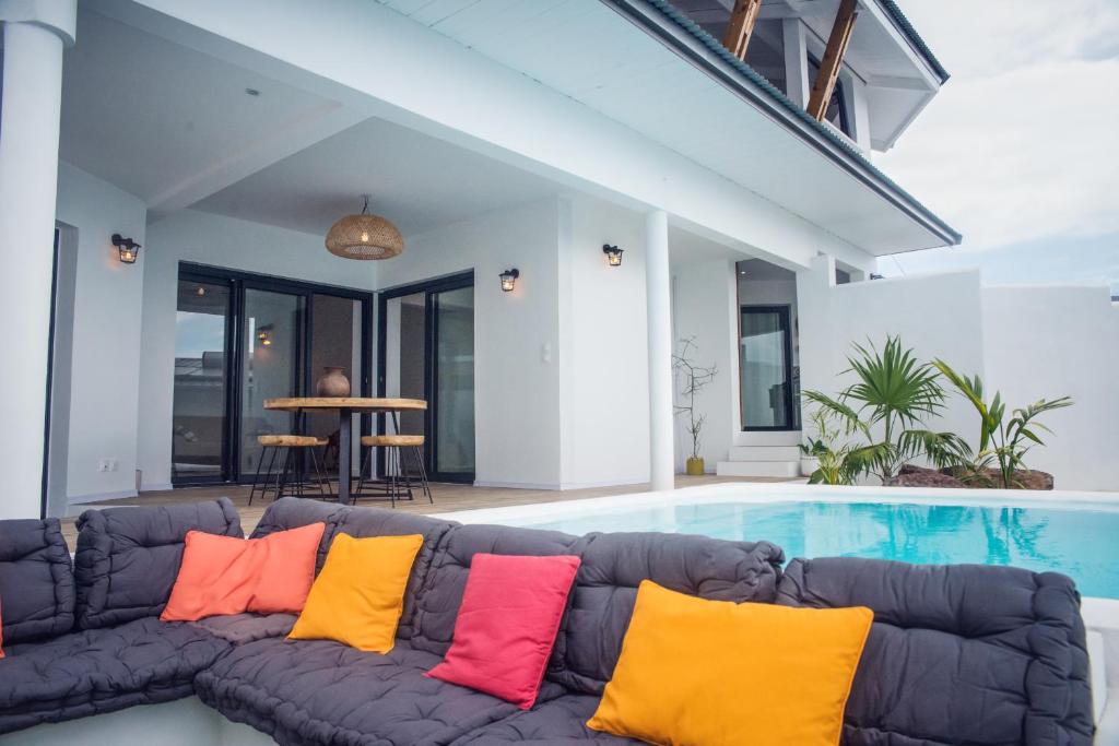 圣勒Villa romantique, Rêve d'ailleurs, saint leu, la Réunion的游泳池旁的沙发,配有色彩缤纷的枕头