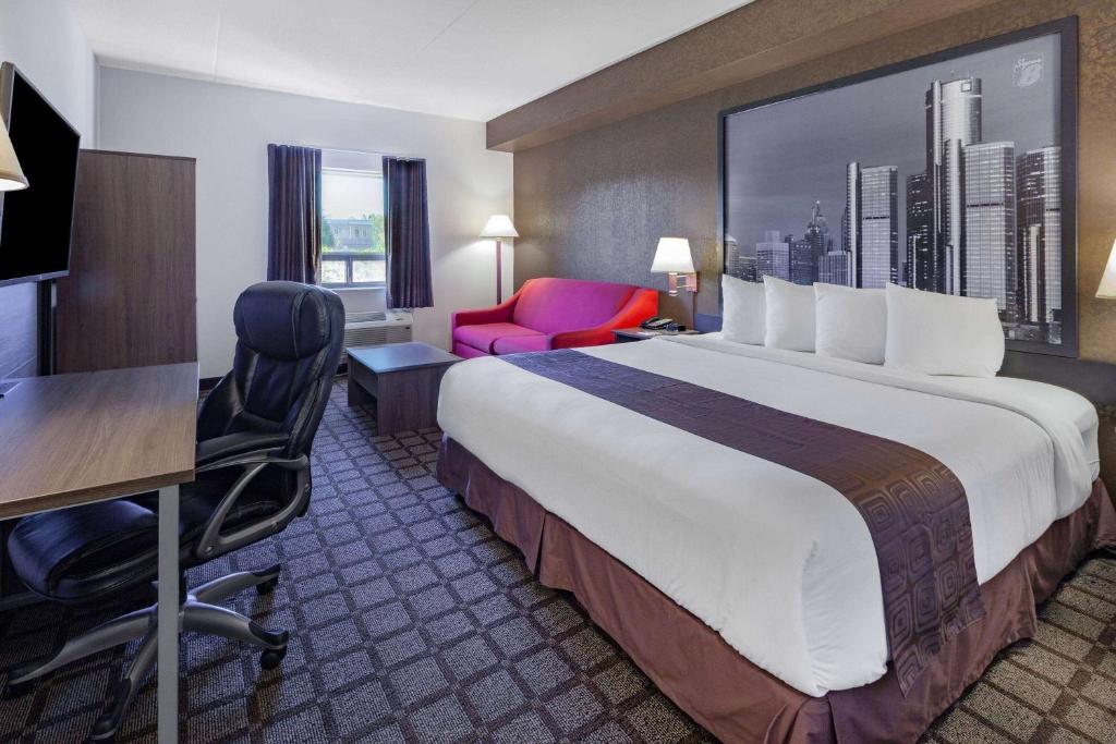 温莎温莎大使桥速8汽车旅馆的酒店客房设有一张大床、一张桌子和椅子。