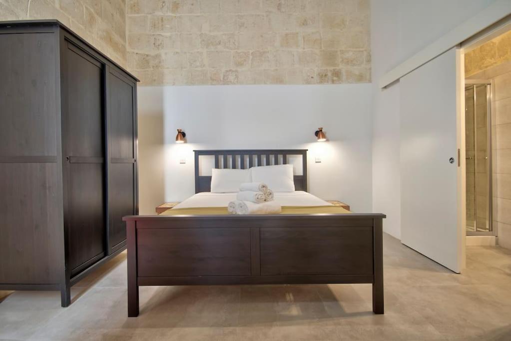 瓦莱塔Vallettastay Old Lodge Apartment 3的一间卧室配有一张大床和木制梳妆台