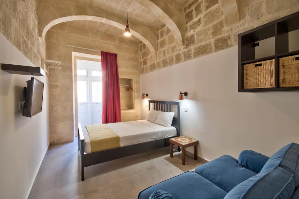 瓦莱塔Vallettastay Old Lodge Apartment 4的一间卧室配有一张床和一张蓝色的沙发